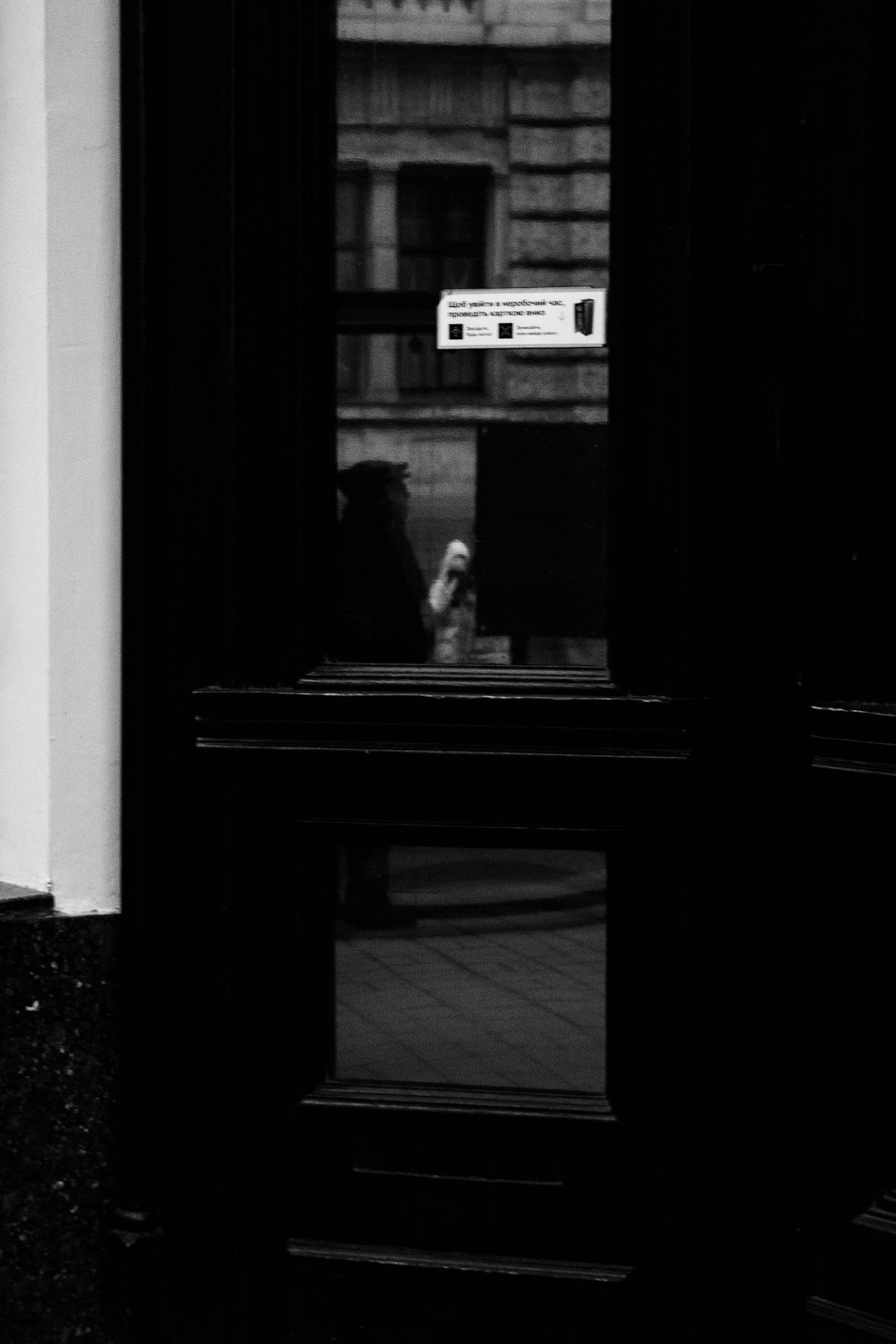 a black and white photo of a person looking out a window