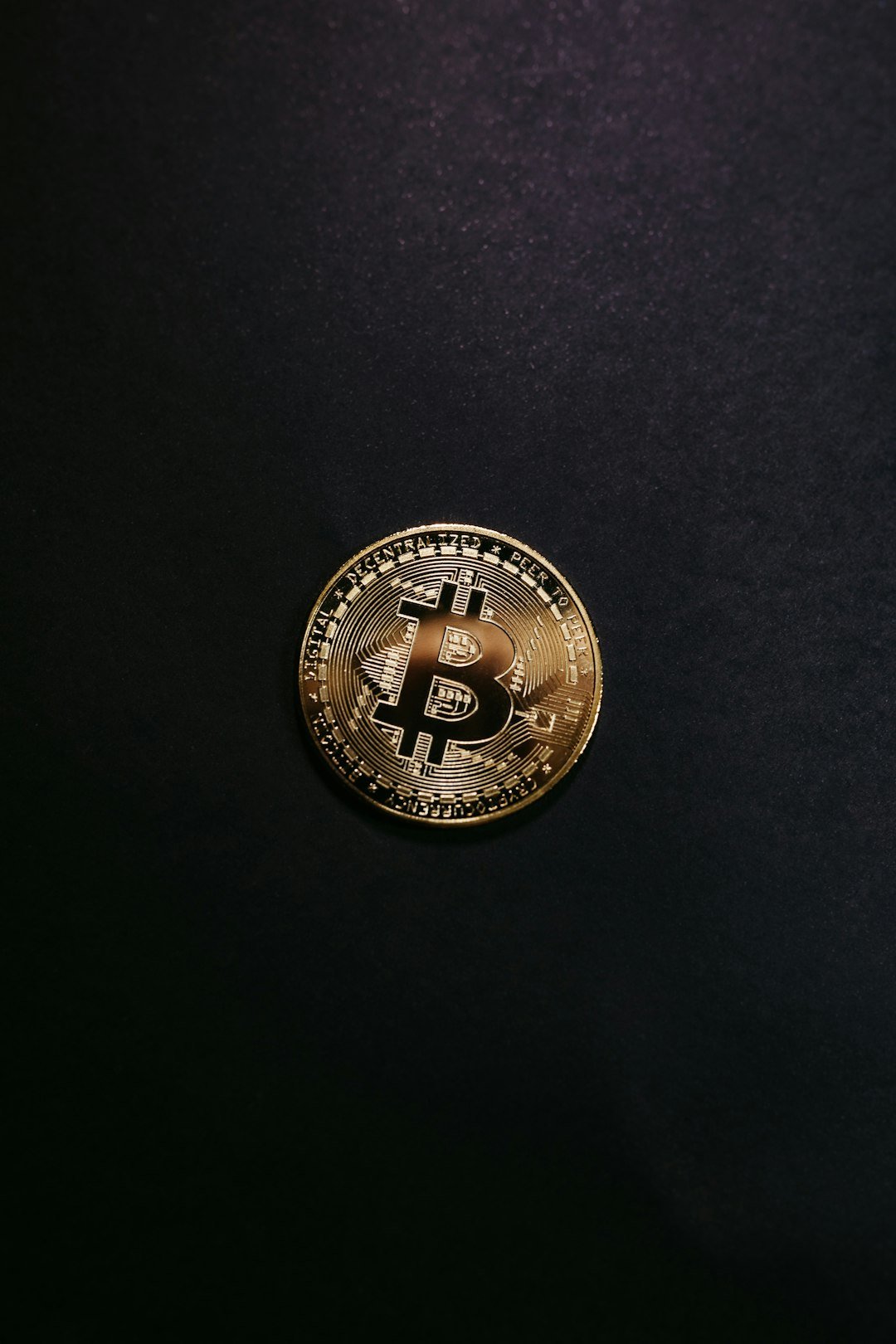 a bit coin sitting on top of a black surface