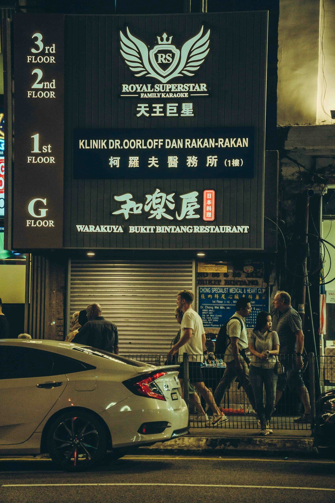 Nighttime street scene shows a restaurant and clinic sign.