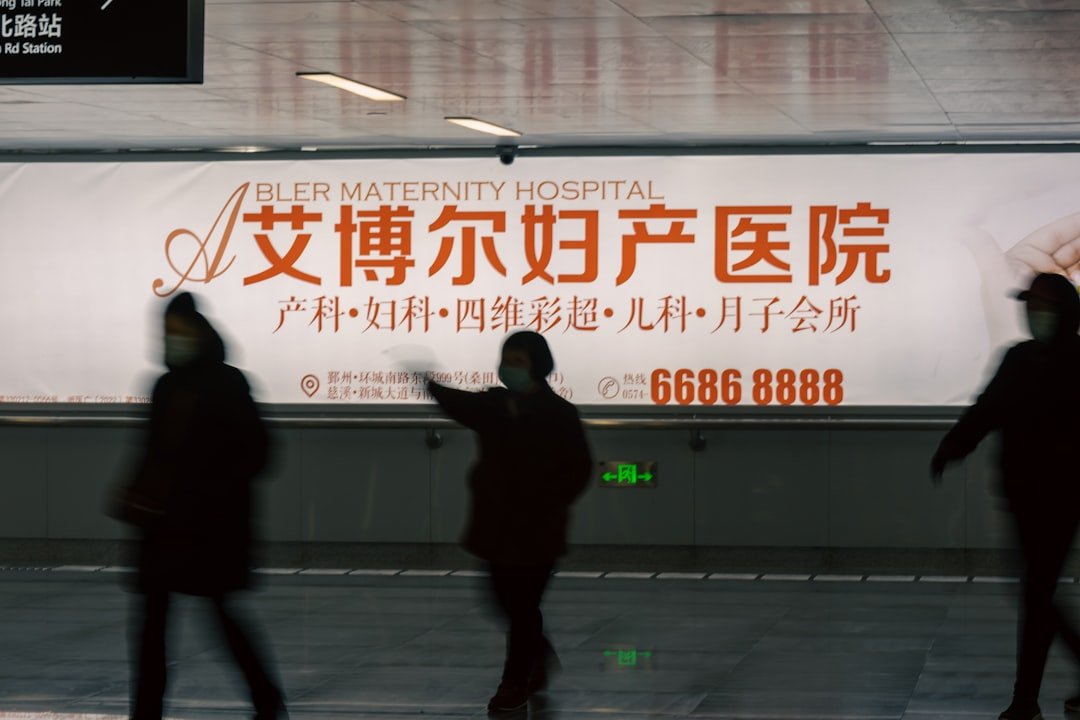 a group of people walking past a hospital sign